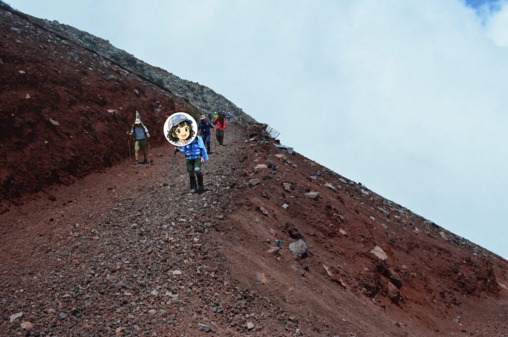 じゃりじゃりの下山ルートを降りる登山者の写真