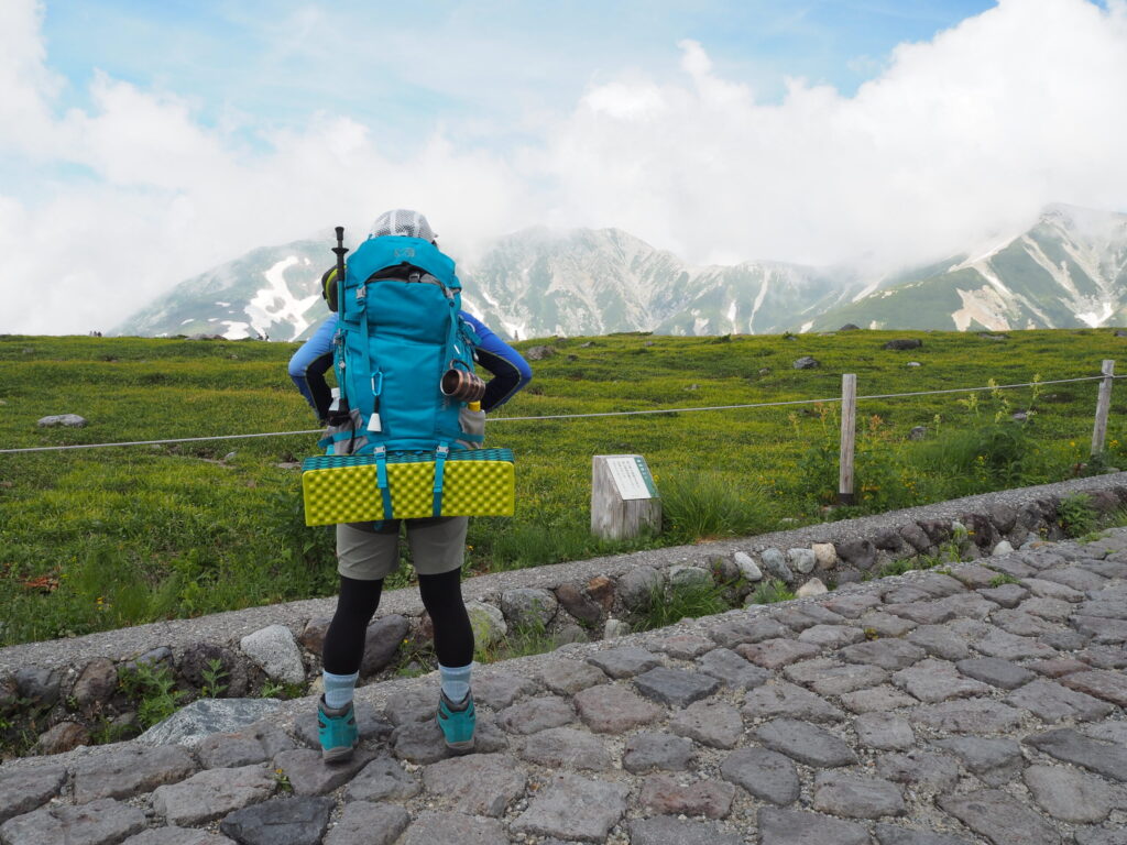 荷物いっぱいで歩く登山者の写真